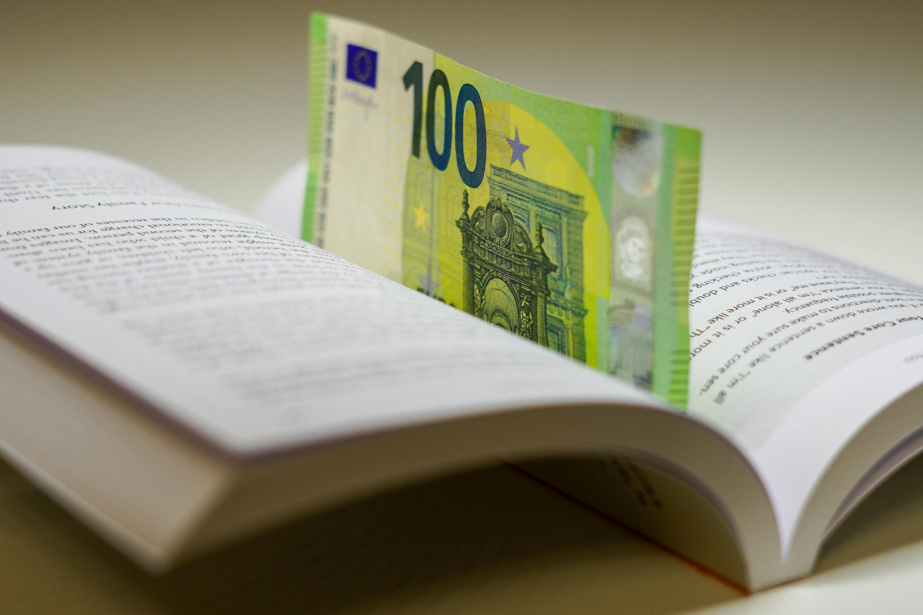 A 100 euro bill used as a bookmark between open pages of a book, symbolizing wealth and knowledge.