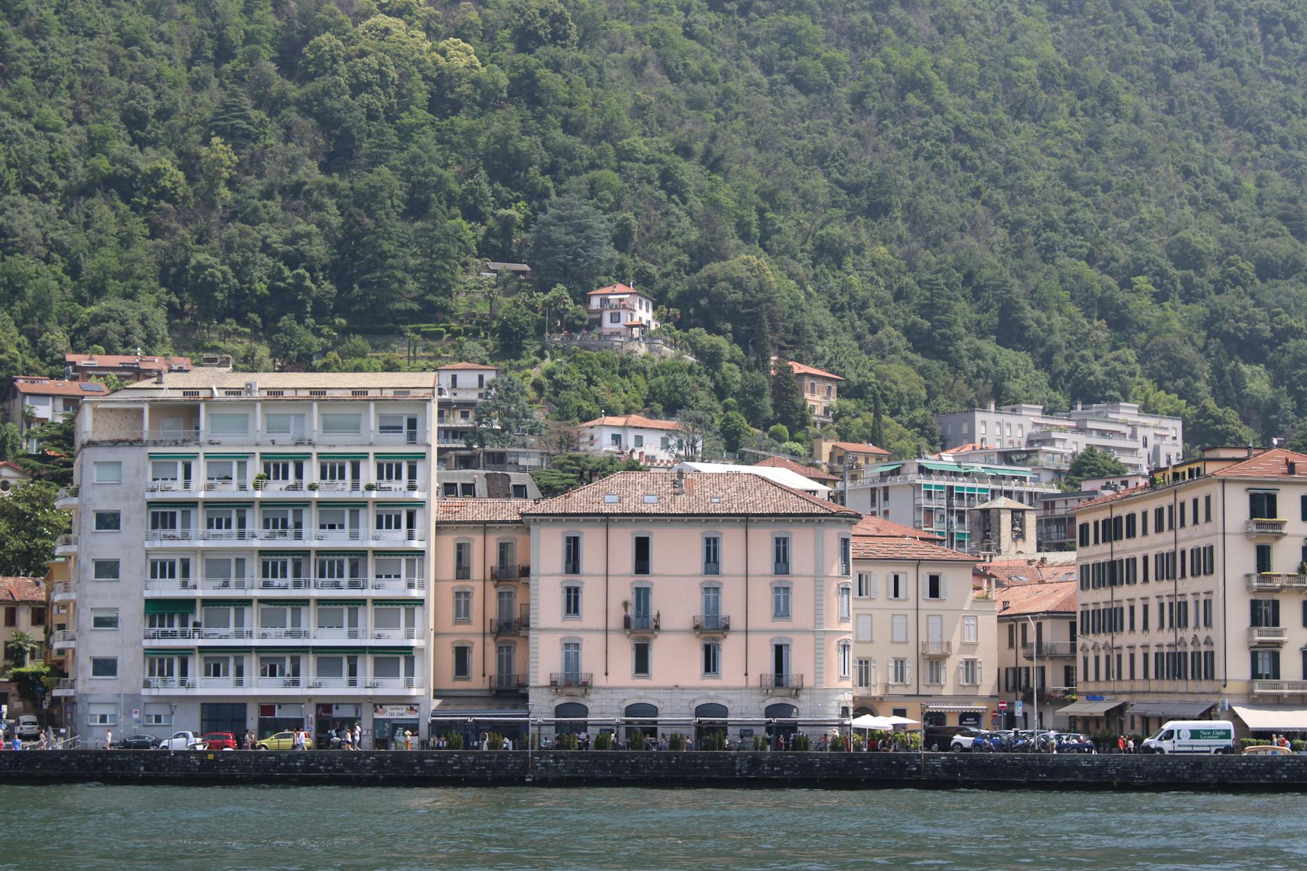 A picturesque view of Lake Como's lakeside architecture with lush green hills in the background.