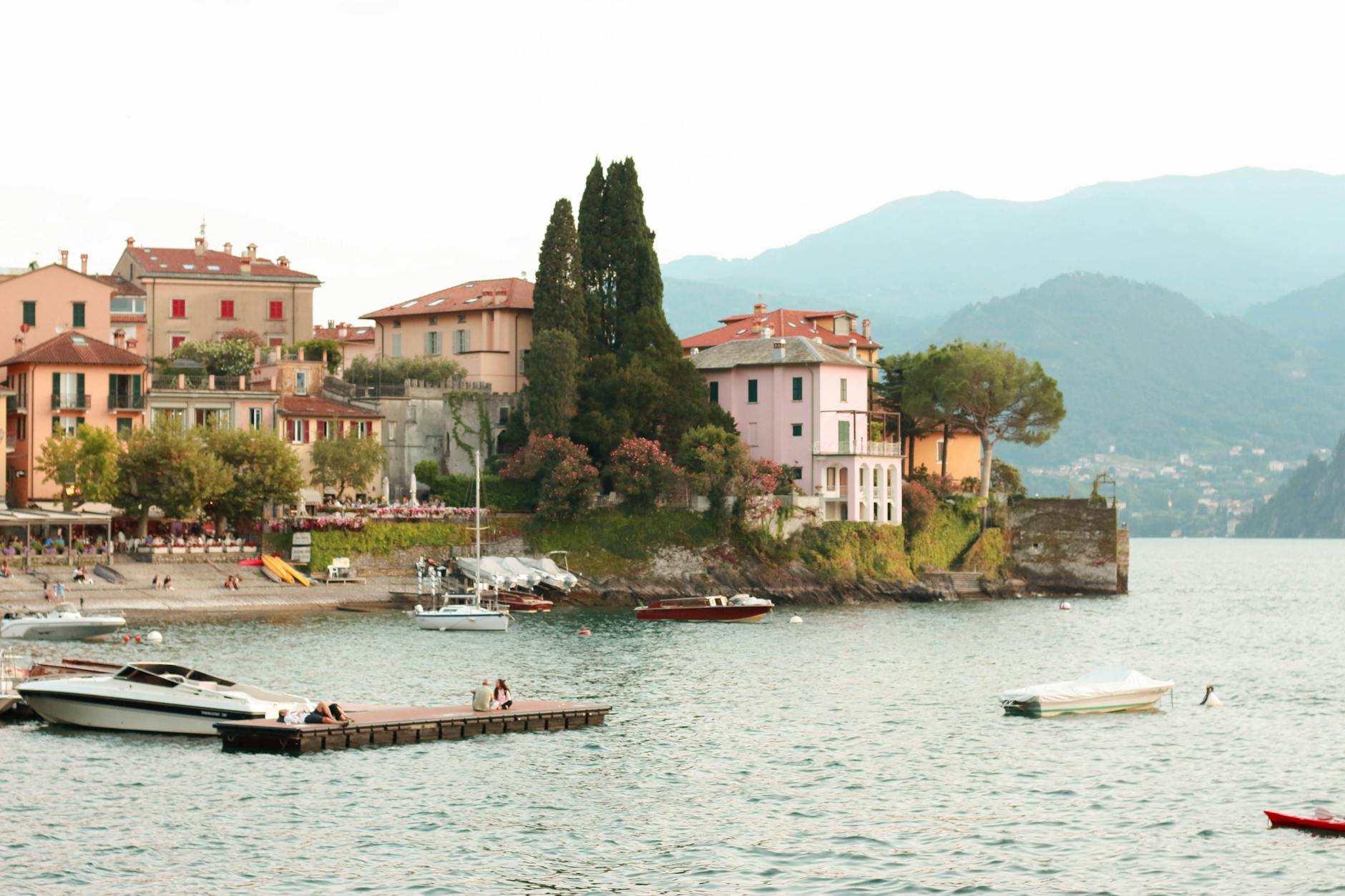 Charming lakeside town in Lake Como with boats and mountains in the backdrop.
