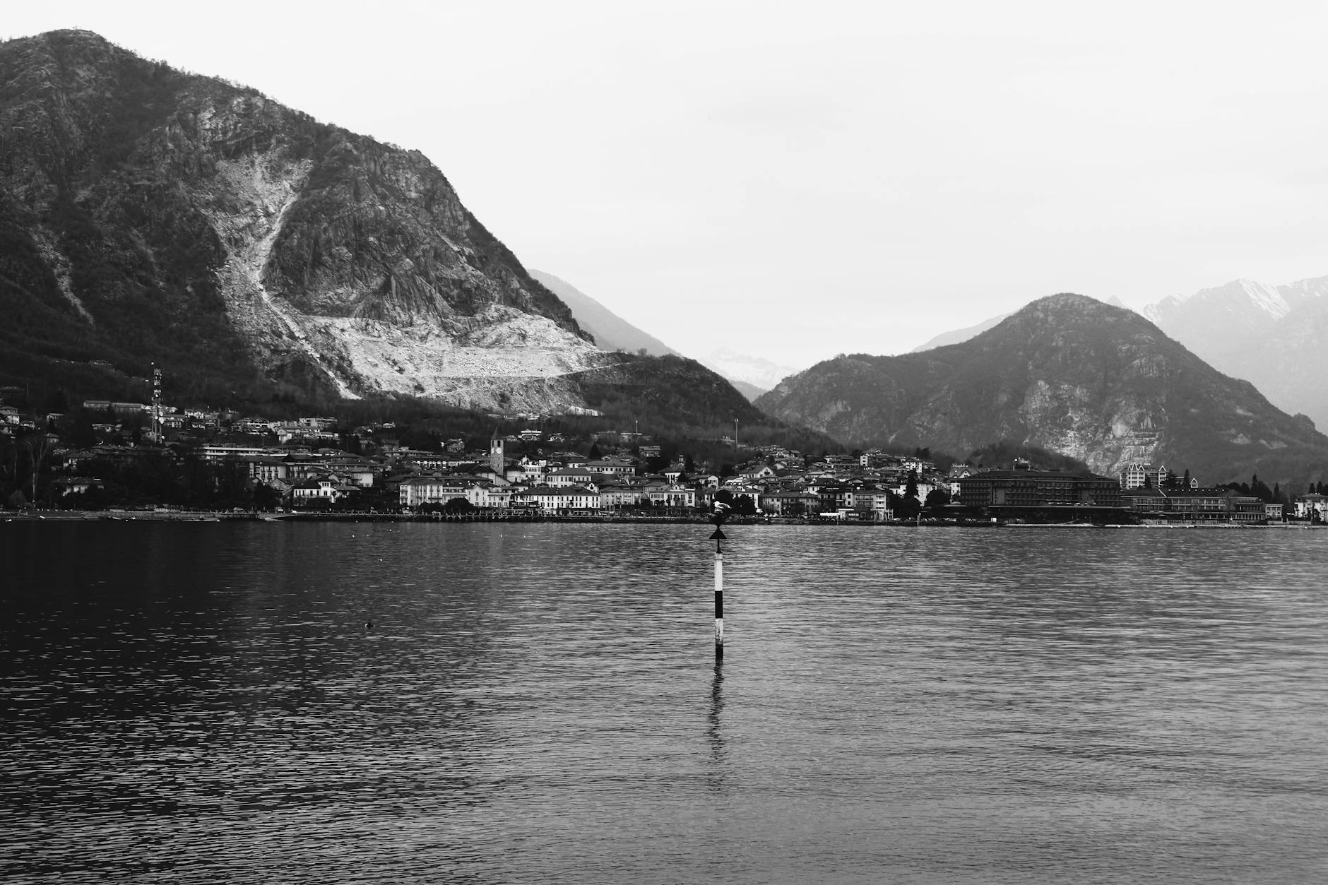 Explore the serene beauty of Lake Como with surrounding mountains in a timeless black and white capture.
