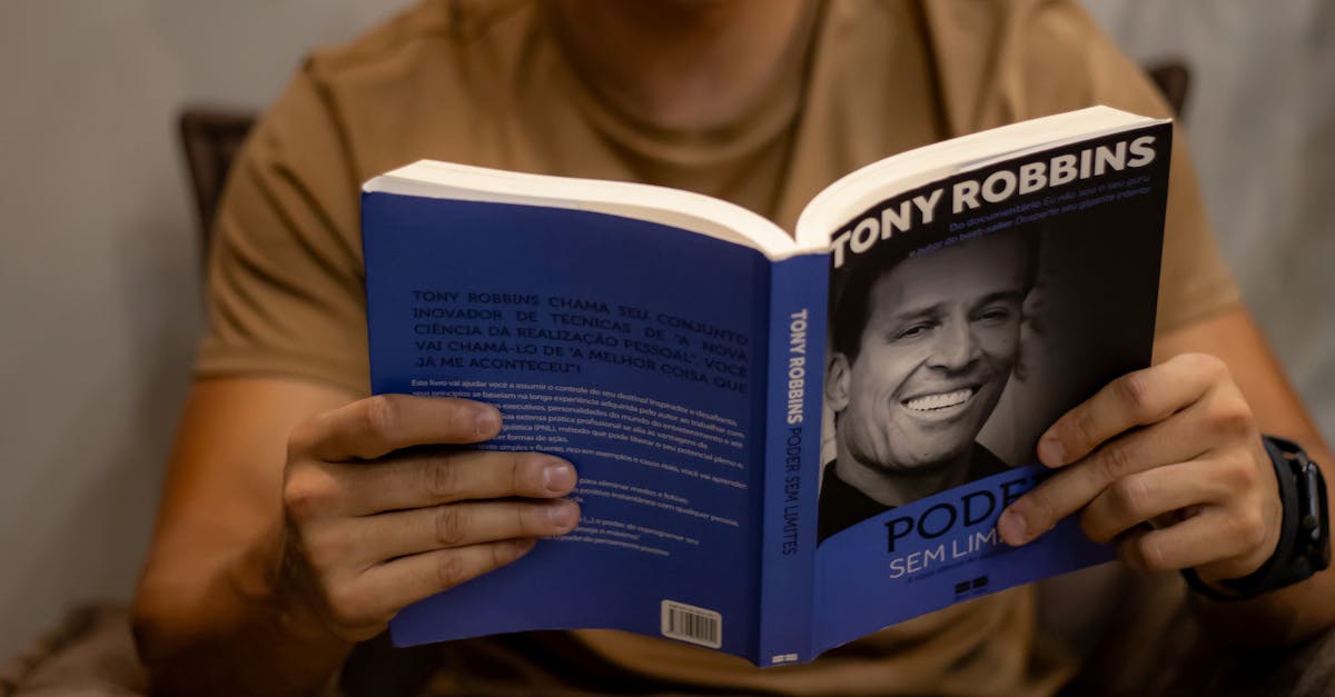 Close-up of a person reading 'Poder Sem Limites' by Tony Robbins indoors.