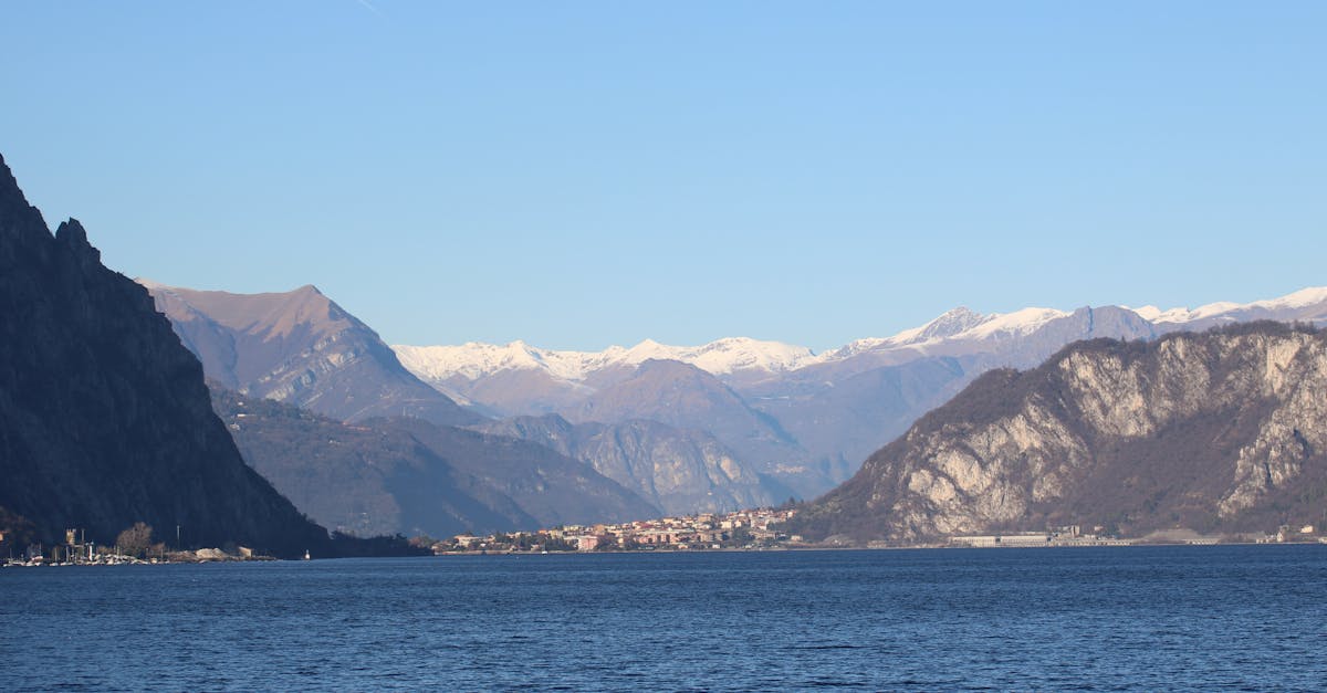 Beautiful view of Lake Como framed by snow-capped Alpine mountains under a clear blue sky.