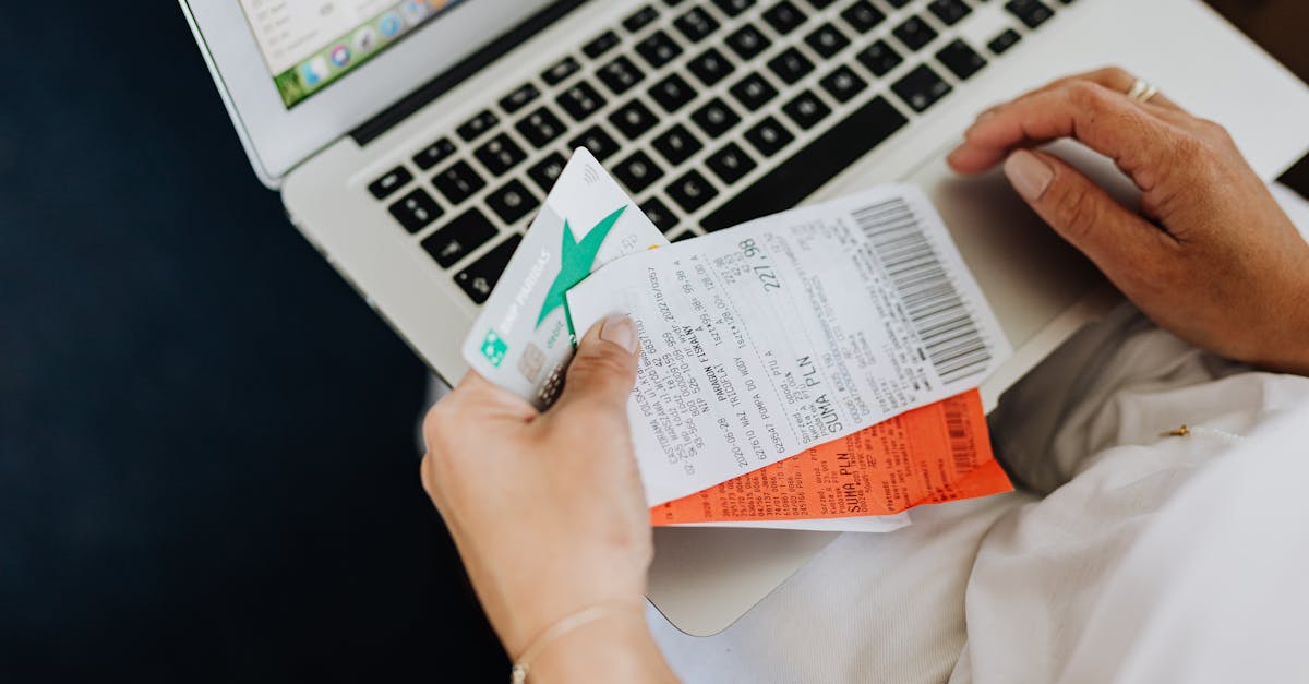 Close-up of hands holding receipts and a bank card in front of a laptop, representing online shopping and e-commerce.