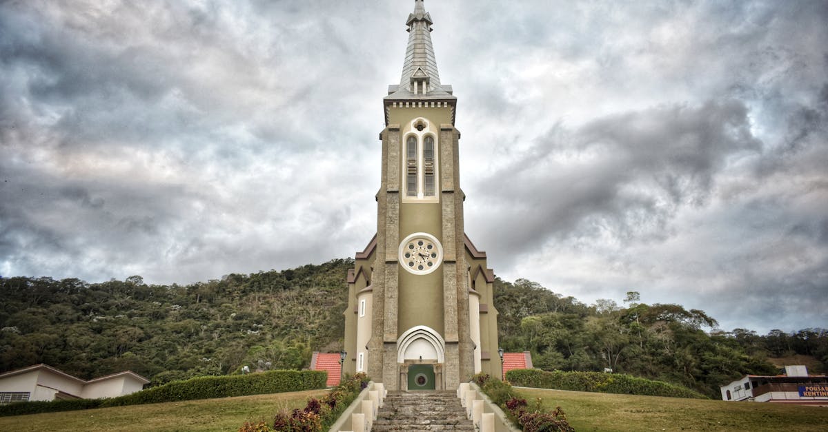Beautiful Igreja Matriz Church in Santa Maria Madalena, Brazil surrounded by hills under a cloudy sky.