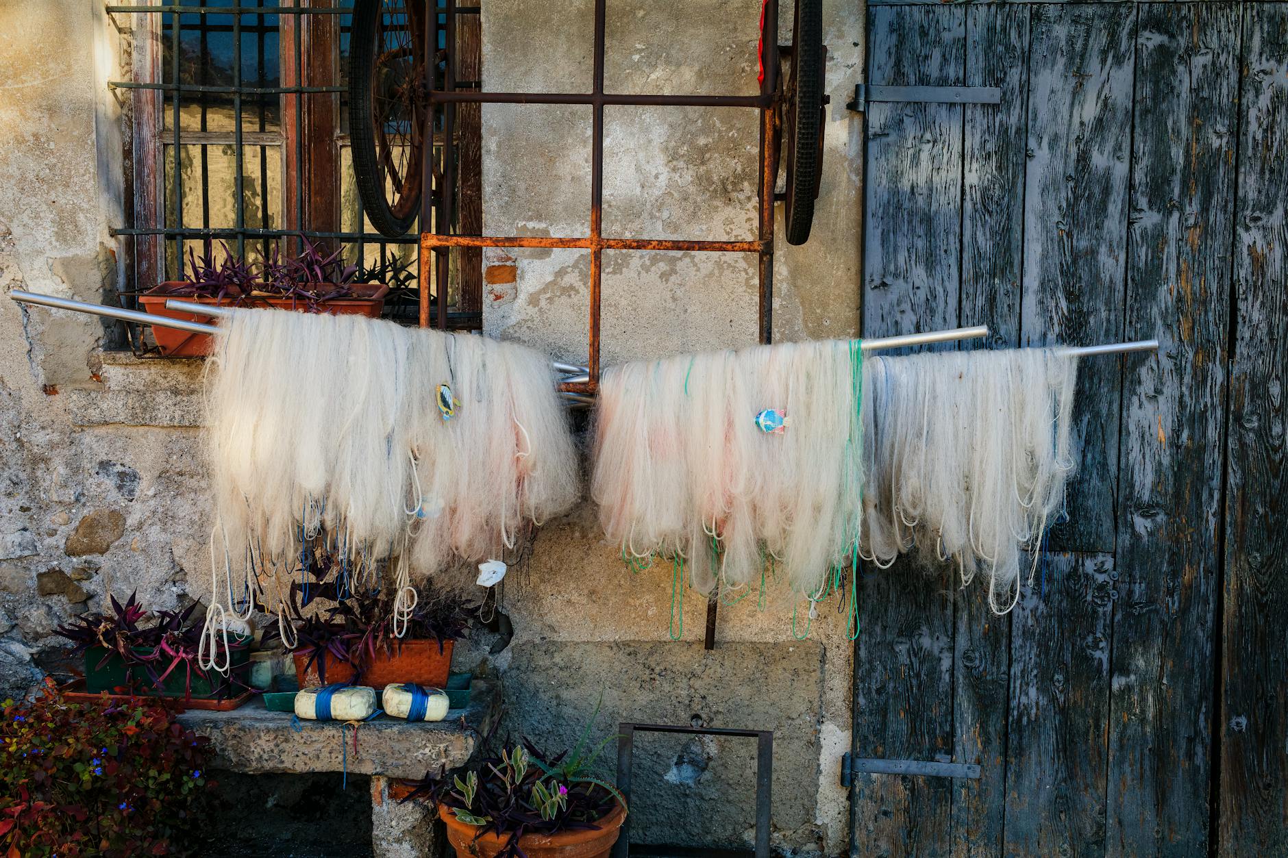 Fishing nets drying on a rustic wall in Como, Italy, showcasing traditional charm.