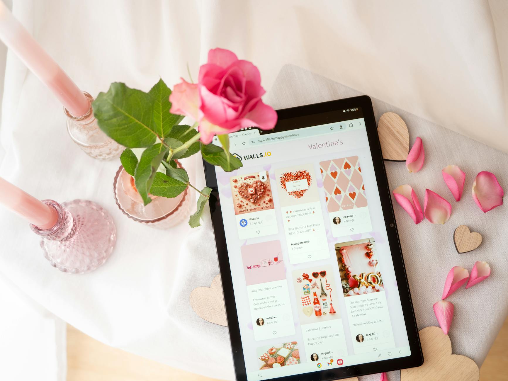 Flat lay of a tablet displaying Valentine's Day content with a pink rose and petals, perfect for romantic themes.