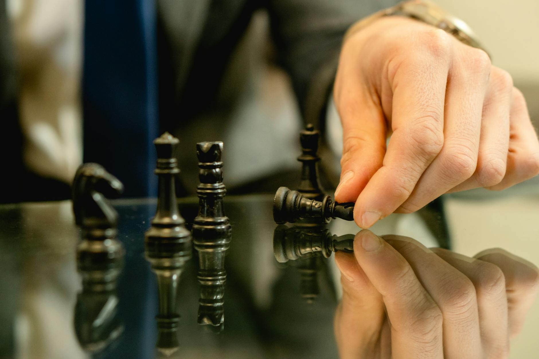 Hand moves chess piece in strategic game setting, reflecting planning and decision-making.