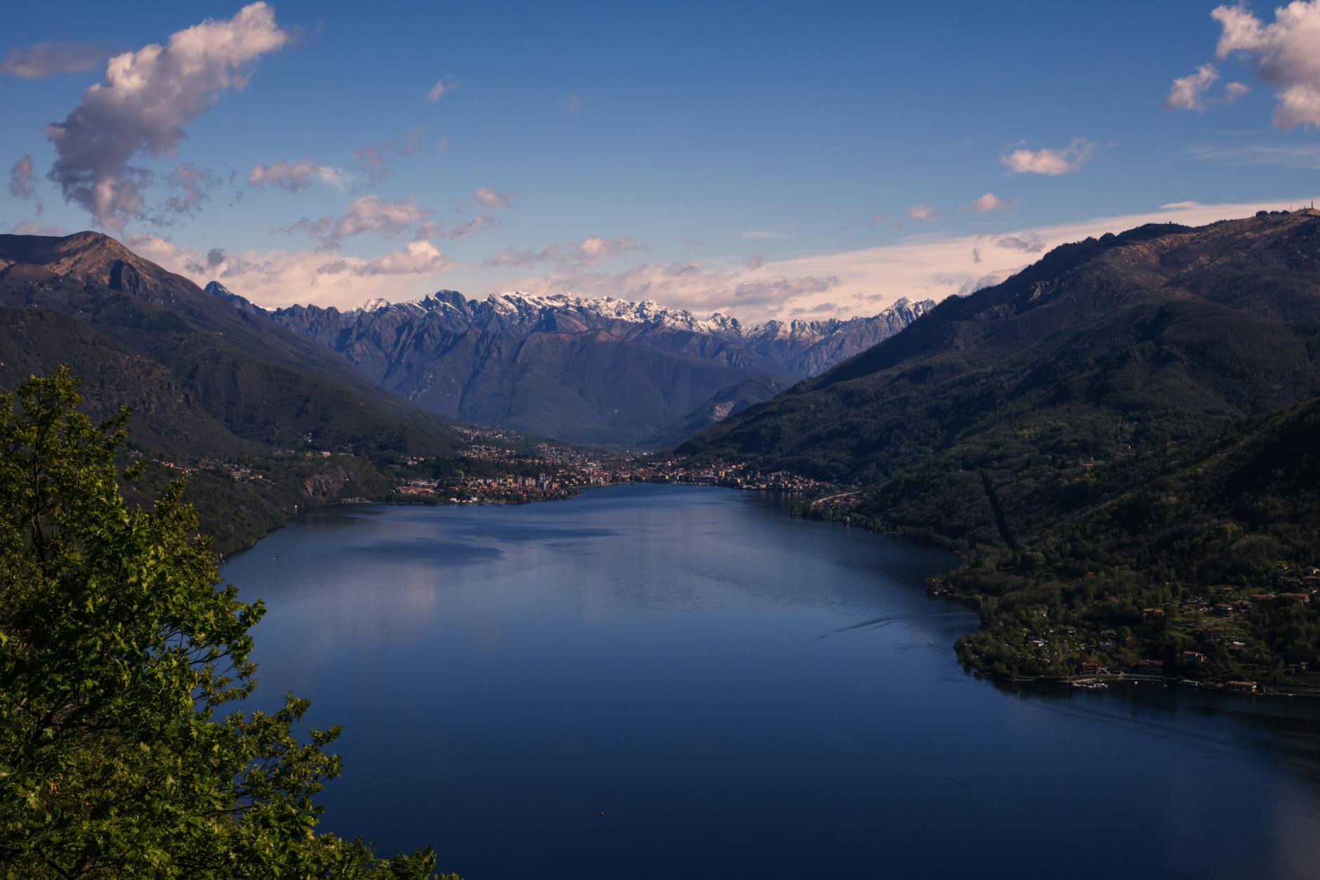 Stunning view of Lake Como surrounded by lush hills and distant snow-capped Alps.