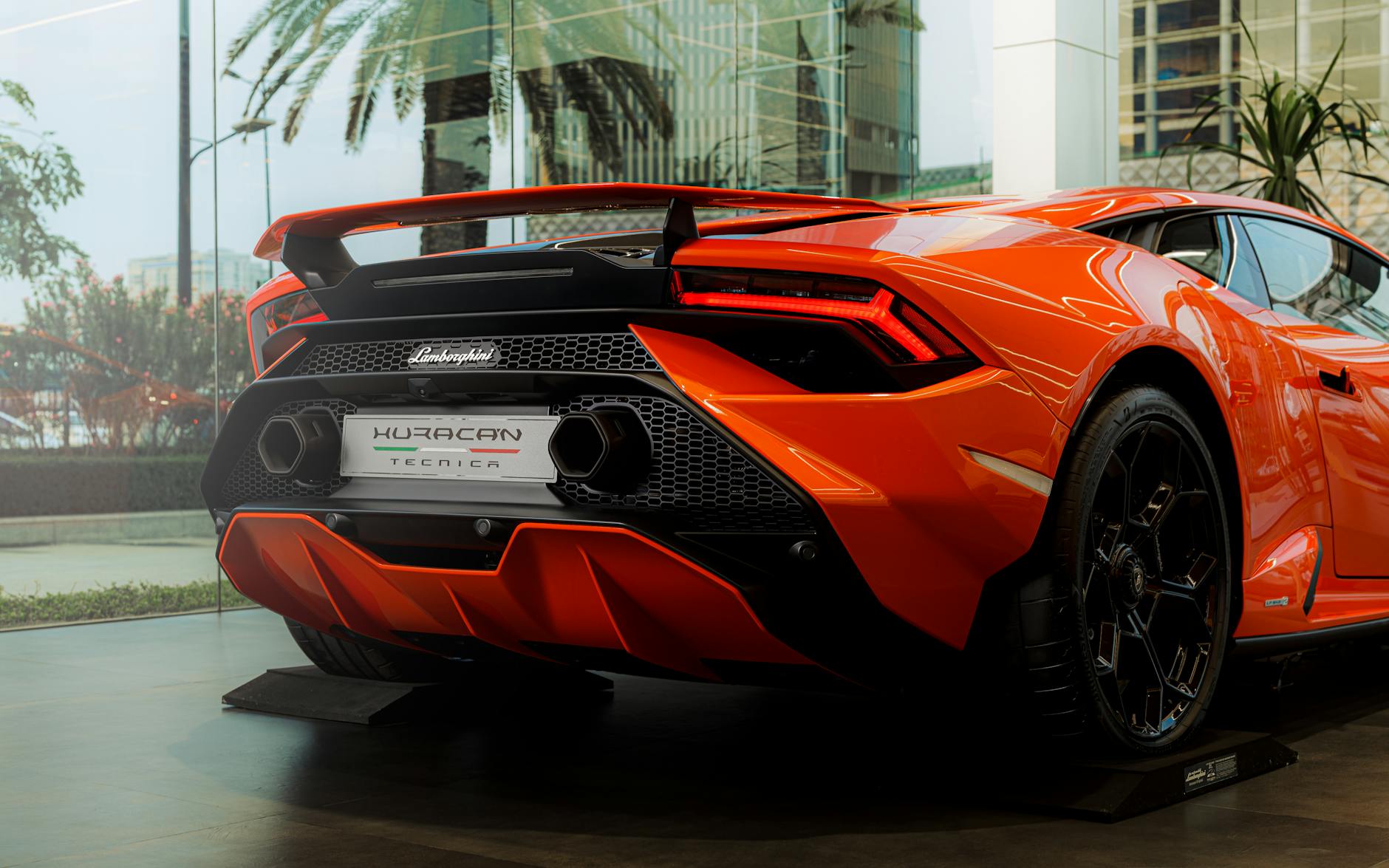 A sleek orange Lamborghini Huracan Tecnica showcased indoors, exuding style and luxury.