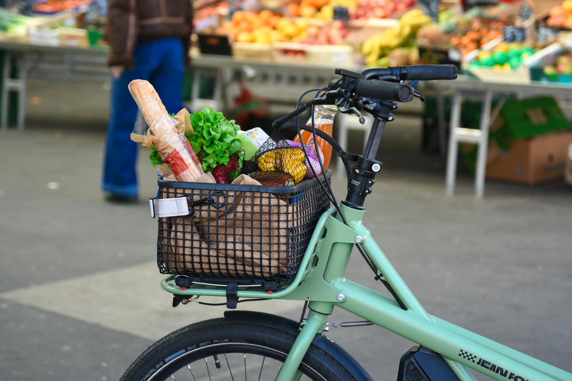 An e-bike with a loaded basket of groceries at a vibrant outdoor market in France.