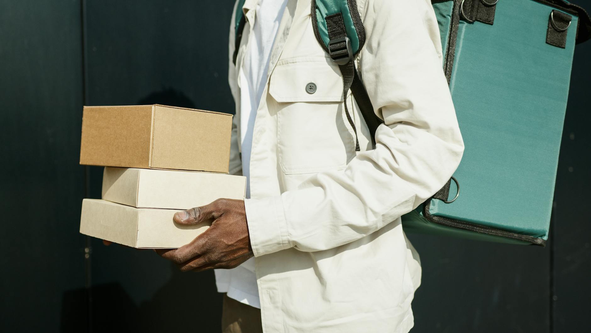 Close-up of a delivery person holding cardboard packages outdoors, showcasing modern urban logistics.