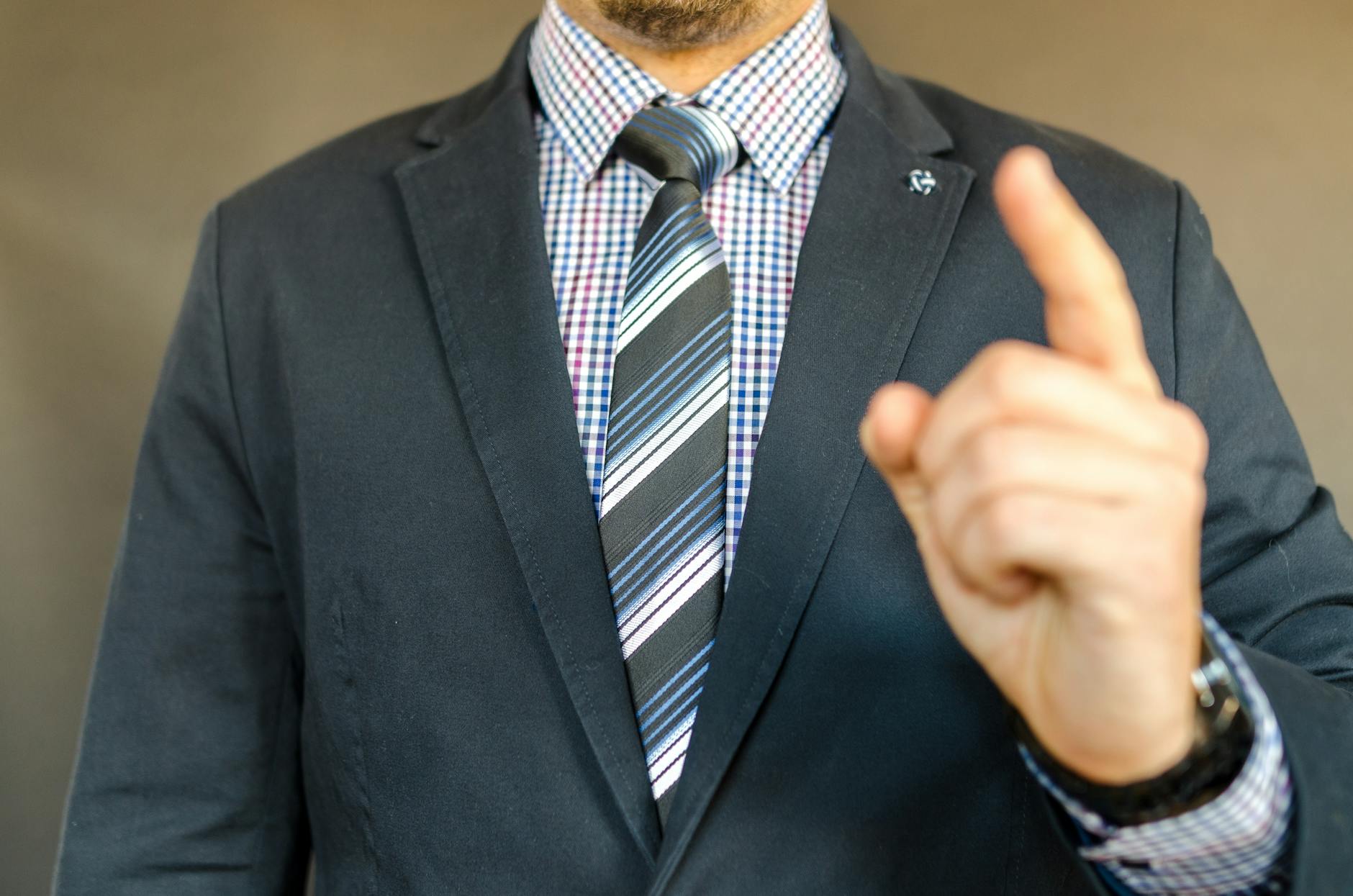 Close-up of a man in a suit making a gesture, symbolizing instruction or guidance.