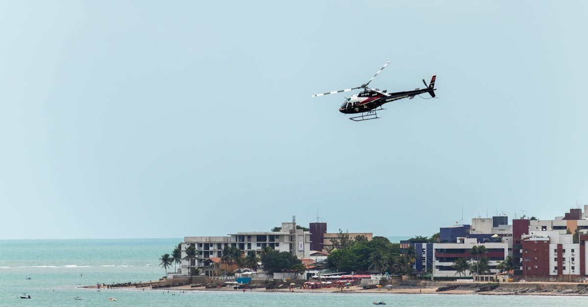 Helicopter flying over João Pessoa beach with buildings in view.