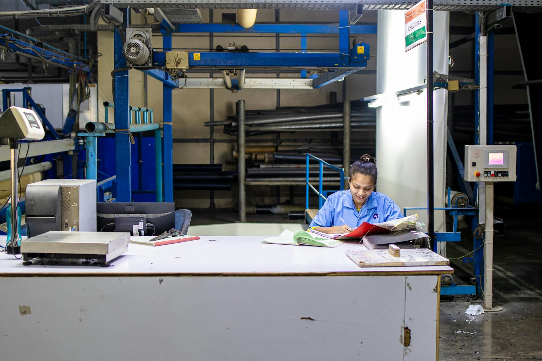 Female worker in a textile factory analyzing production documents at a desk.